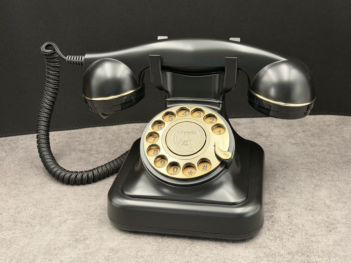 Black rotary telephone with brass dial