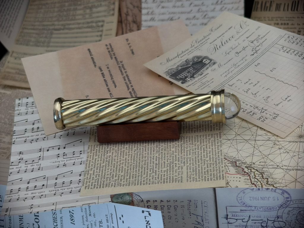 Brass teleidoscope resting on a wooden stand over archival maps and papers